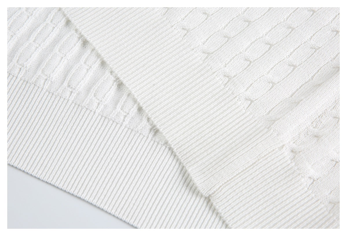 Close-up of overlapping ivory knit fabric with a ribbed edge and raised stitched pattern.