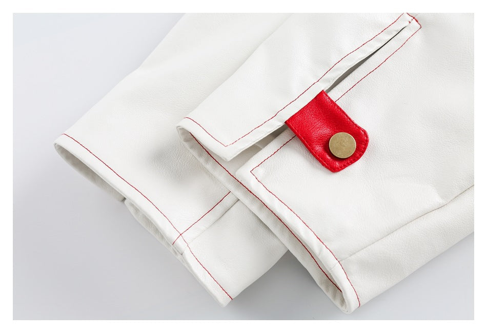 Close-up of a white garment with red-stitched edges and a red snap tab with a brass-colored button.