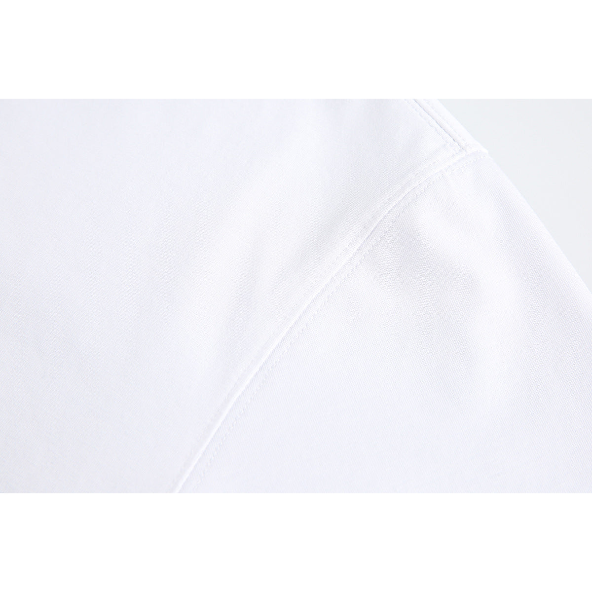 Close-up of white garment fabric with a curved shoulder seam and stitching.