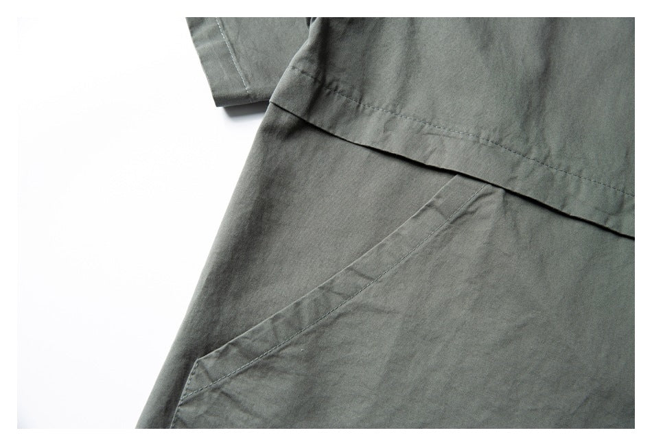 Close-up of a diagonal pocket opening beneath a stitched panel on a dark gray-green shirt.