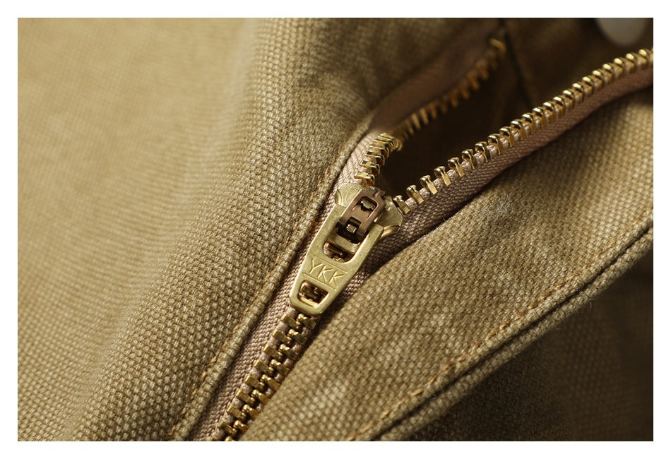 Close-up of the trousers' brass-colored zipper and textured khaki fabric.