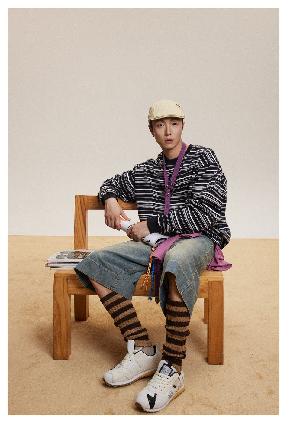 A seated model wears a black long-sleeve shirt with thin white and gray horizontal stripes.