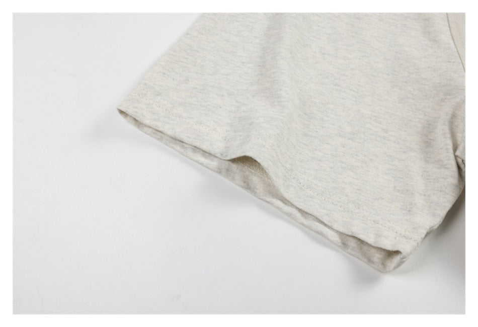 Close-up of a short sleeve and hem on a light heathered garment.