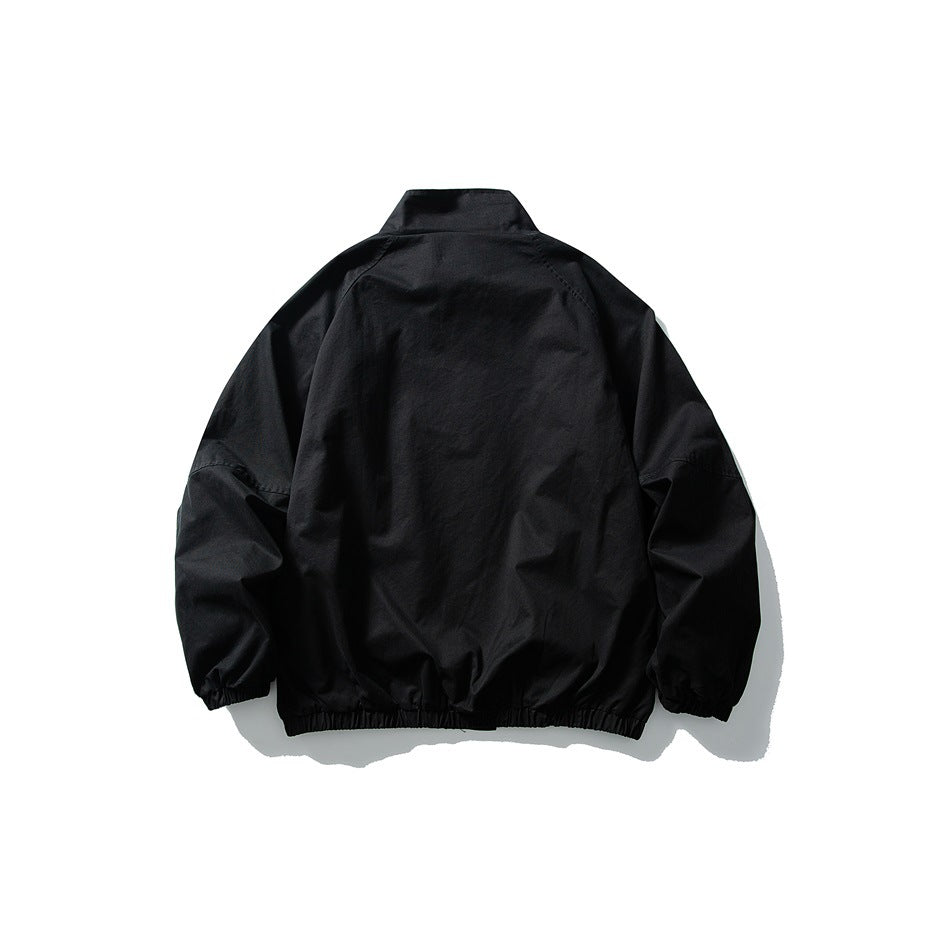 Back view of a black jacket laid flat, showing a stand collar, raglan sleeves and elasticated cuffs and hem.