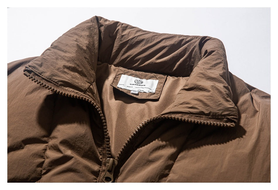 Close-up of a brown jacket's high collar, front zipper, and sewn neck label.