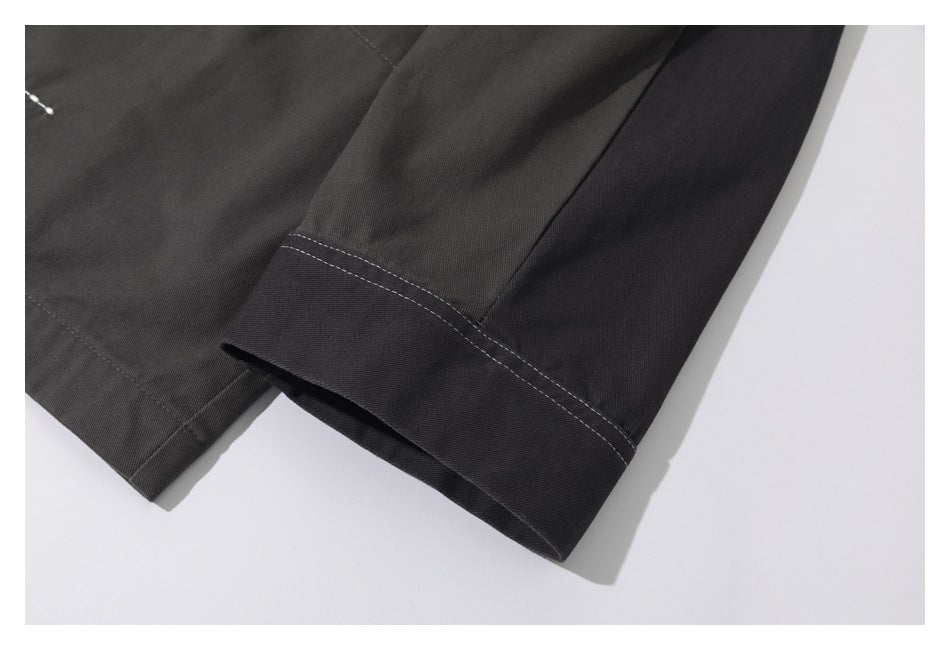 Close-up of a dark charcoal sleeve cuff with white contrast stitching and an adjacent garment panel.