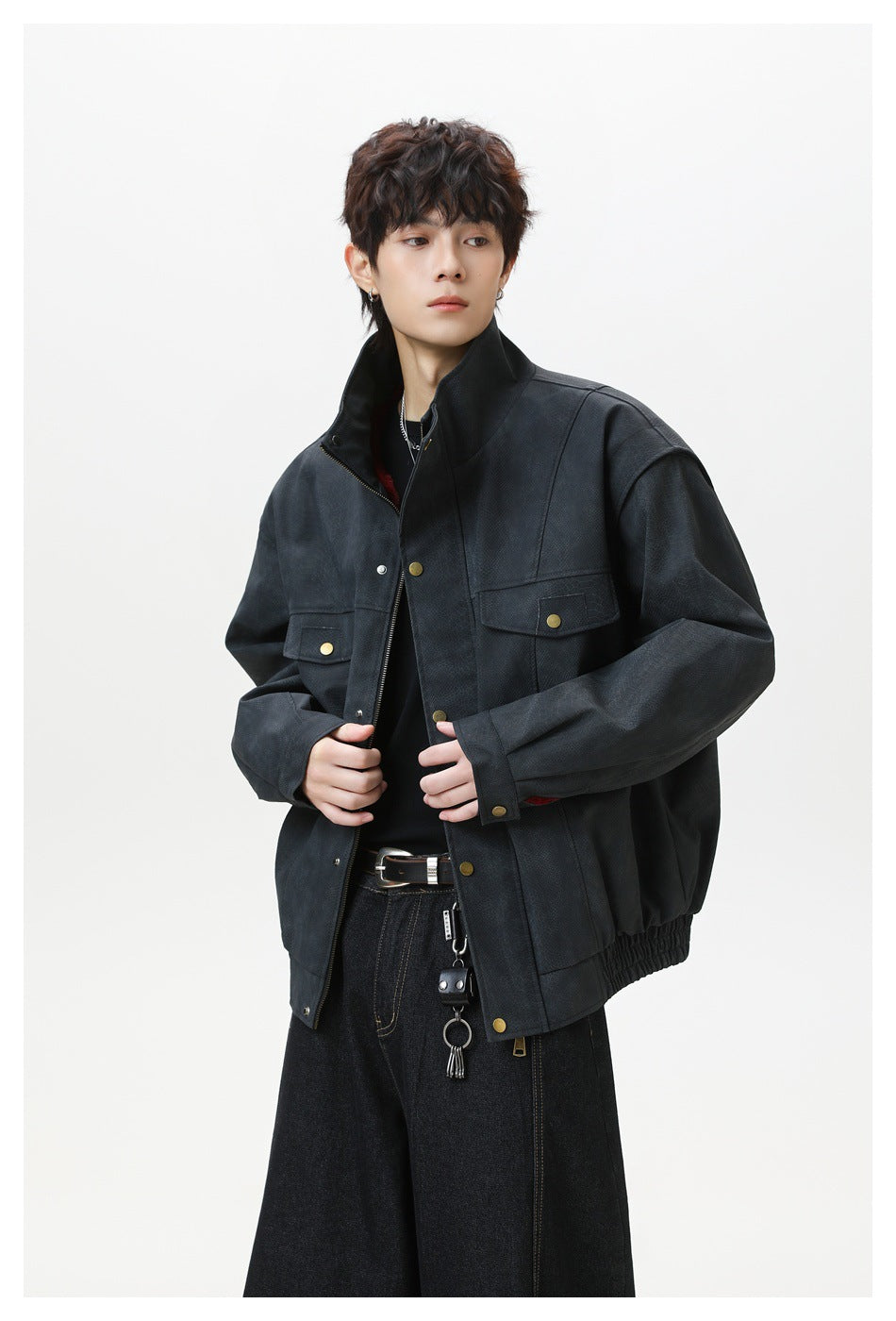 Model wearing a dark charcoal jacket with a high collar, brass-tone snaps, and flap chest pockets.
