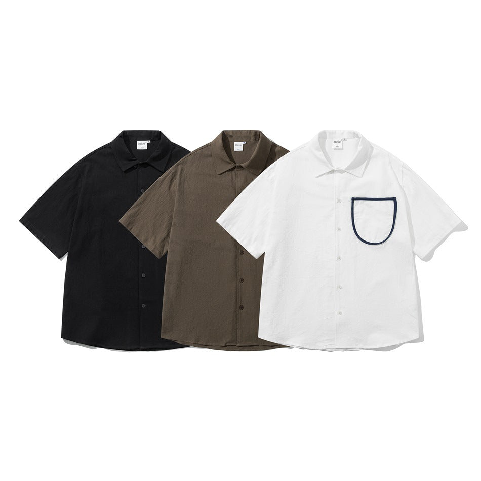 Three short-sleeve button-up shirts in black, brown, and white; the white shirt has dark trim around its chest pocket.