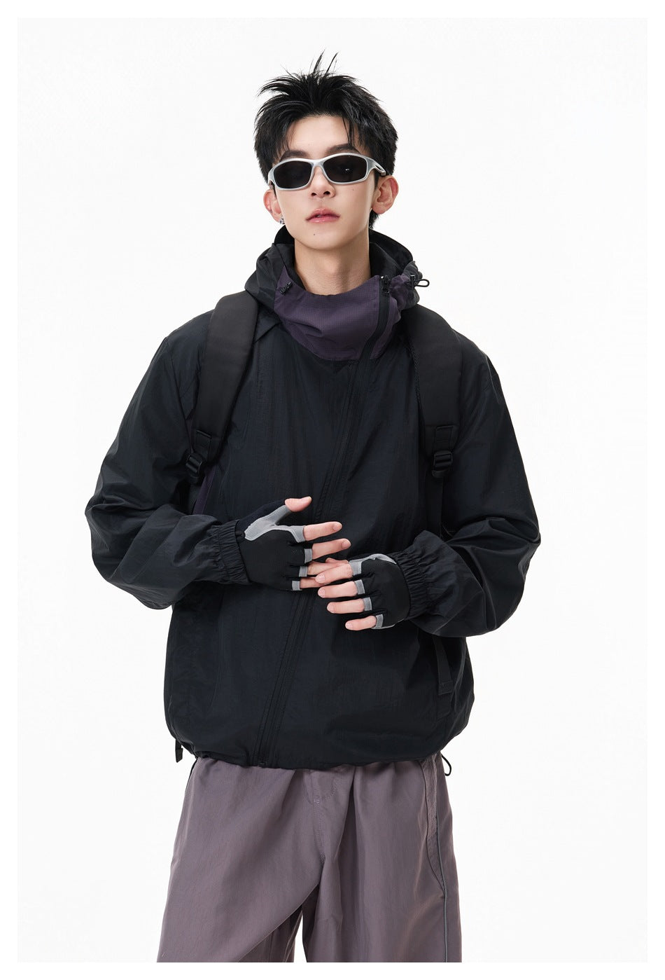 Closer view of a model wearing a black hooded jacket with a high purple-gray neckline and angled front zipper.