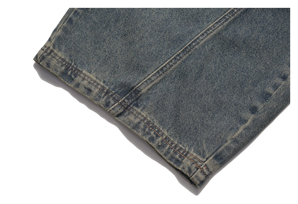 Close-up of the double-stitched hem on a leg of faded dark blue jeans.