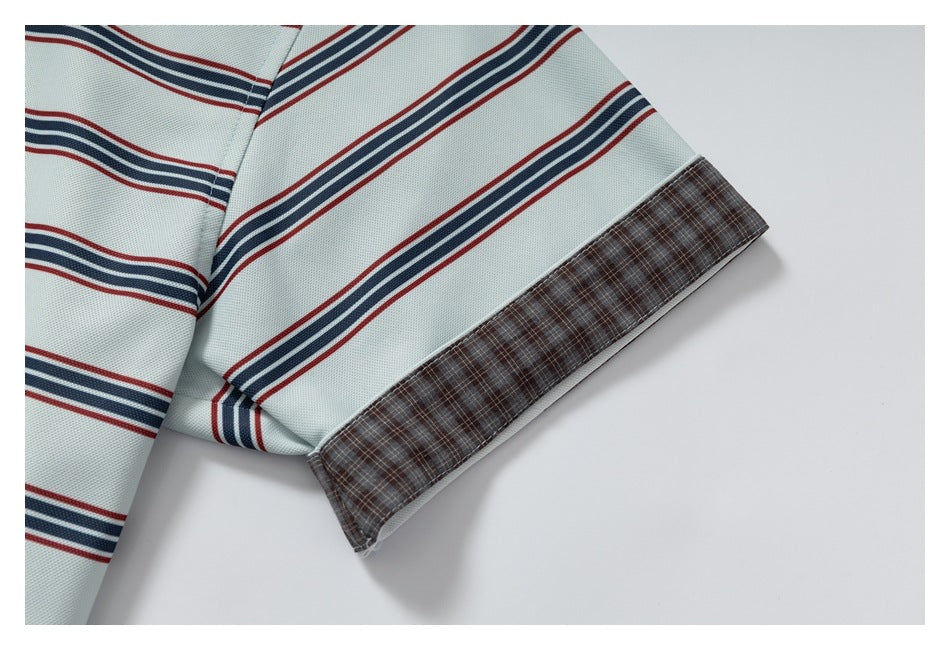 Close-up of a pale shirt sleeve with red and navy stripes and a brown plaid cuff trim.