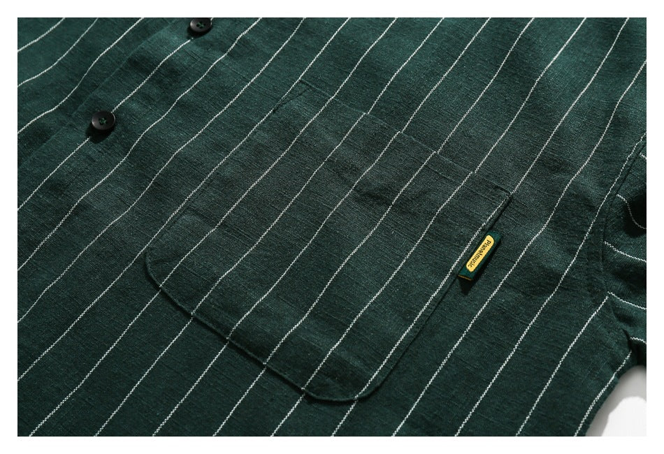 Close-up of the dark green striped shirt's button placket and chest pocket with a small woven tag.
