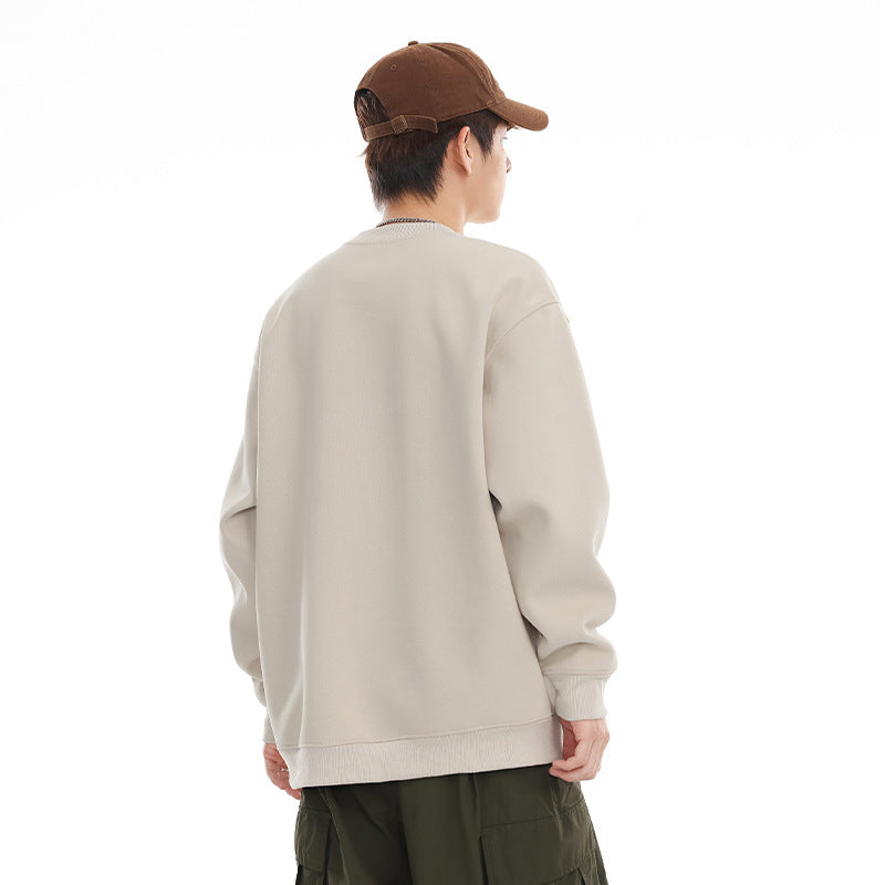 Rear view of a model wearing a light beige crewneck sweatshirt with ribbed cuffs and hem.
