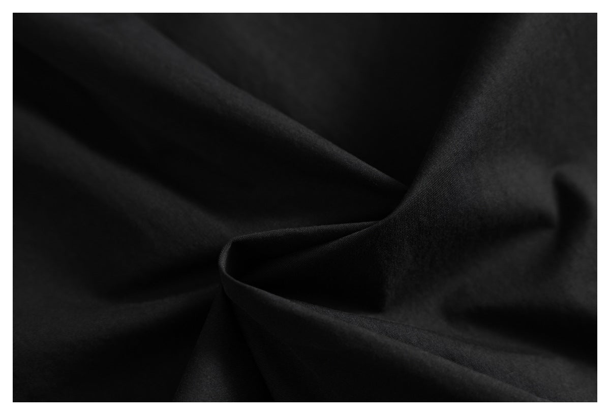 Close-up of black fabric arranged in soft folds, showing its surface texture.