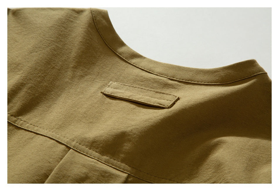 Close-up of the tan garment's rounded neckline and small stitched tab on the back.