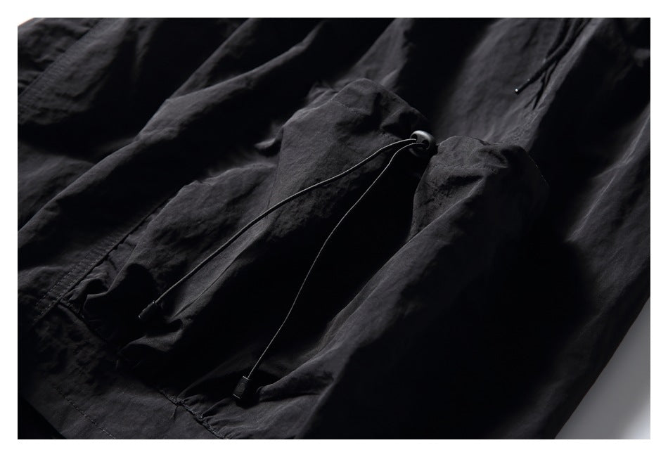 Close-up of black shorts showing an adjustable drawcord and toggle at the hem.
