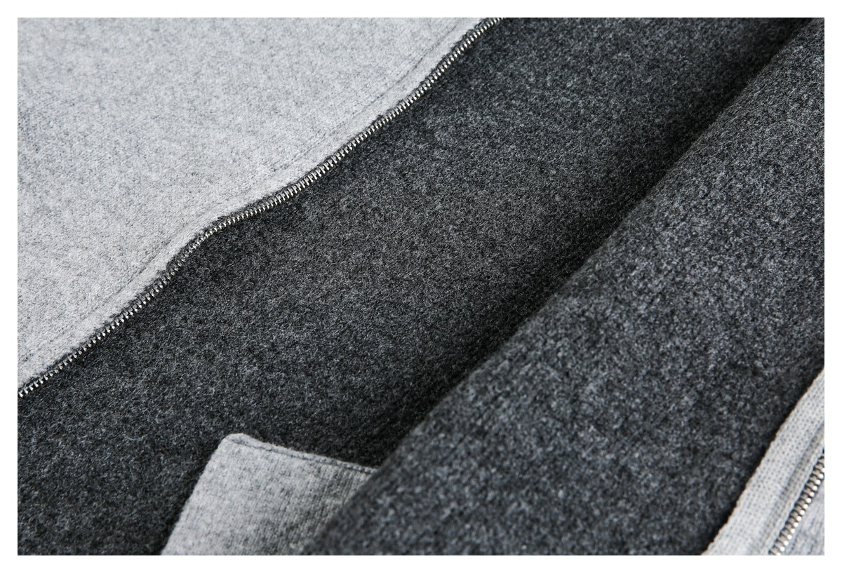 Close-up of an open metal zipper between light gray and charcoal knit panels, with a partial pocket visible.