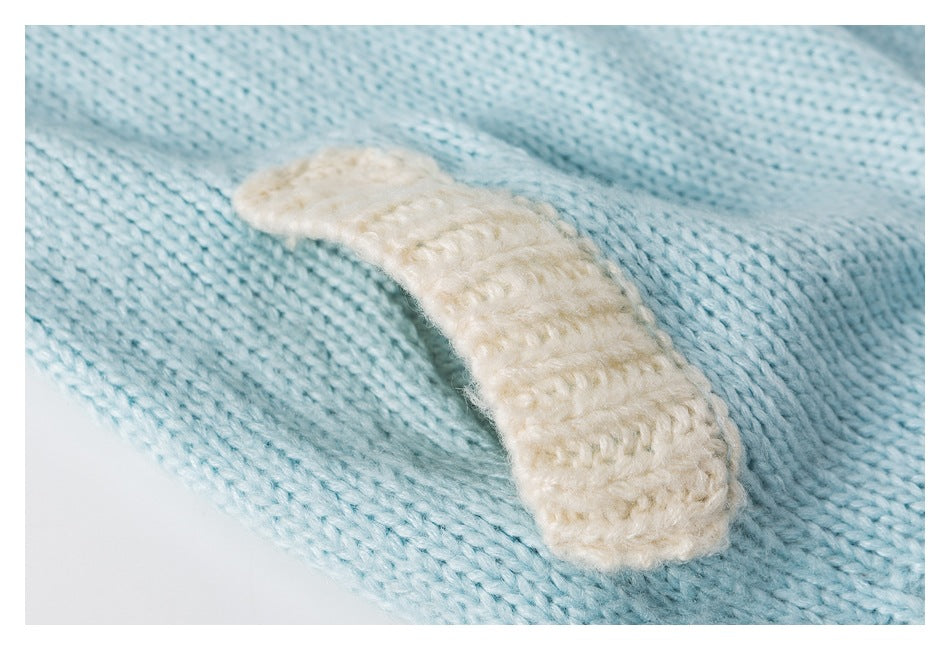Close-up of a raised cream knitted patch on aqua knit fabric.