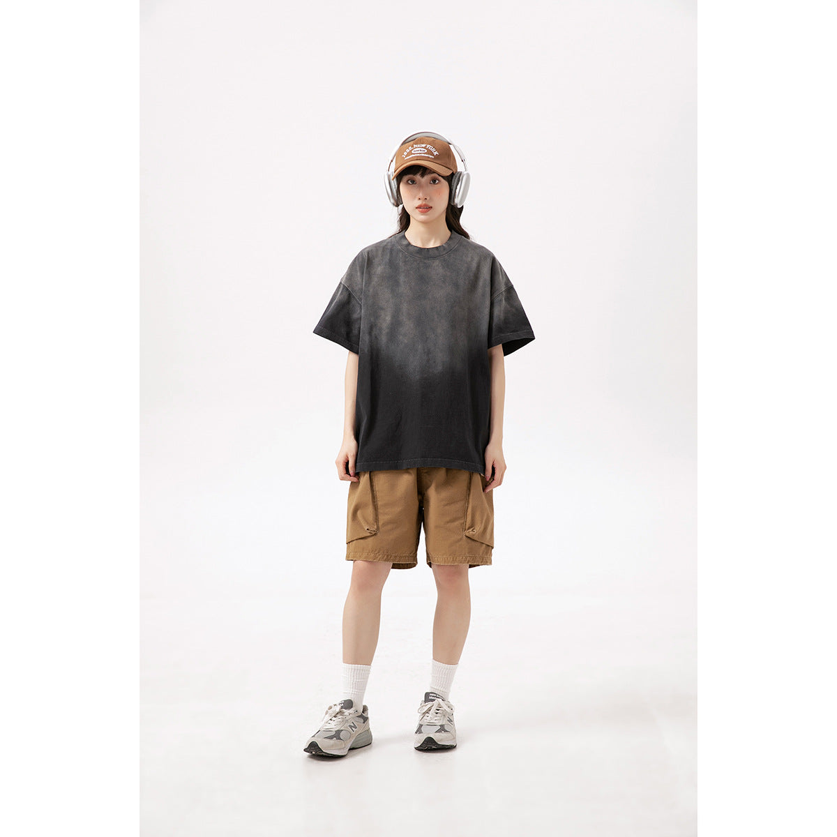 Front view of a model wearing an oversized washed black T-shirt and tan cargo shorts.