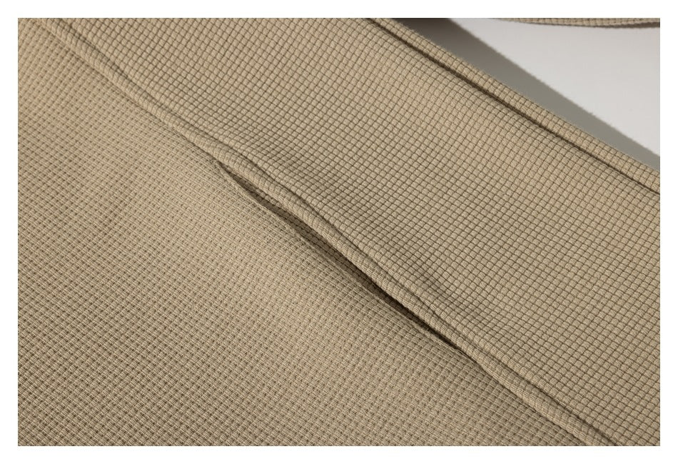 Close-up of the beige jacket's textured fabric and stitched seam.