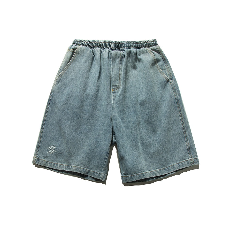 Light blue washed denim shorts front view with elastic waistband, side pockets and small embroidered mark on the leg