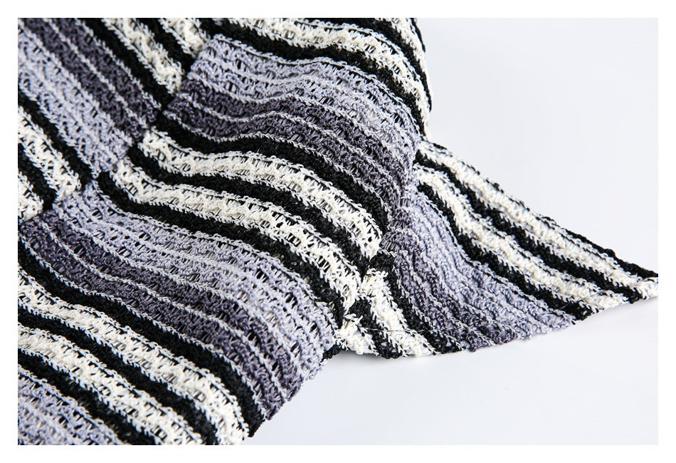 Folded black, gray, and off-white striped open-knit fabric shown against a white background.