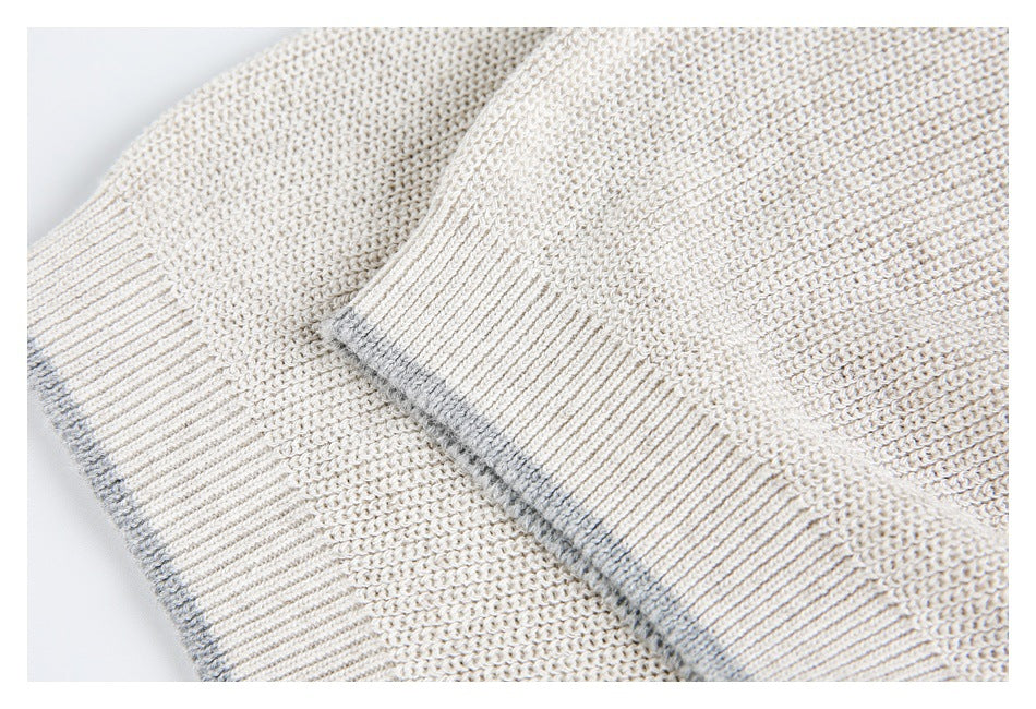 Close-up of two ivory knit sweater cuffs with ribbing and subtle gray edging.