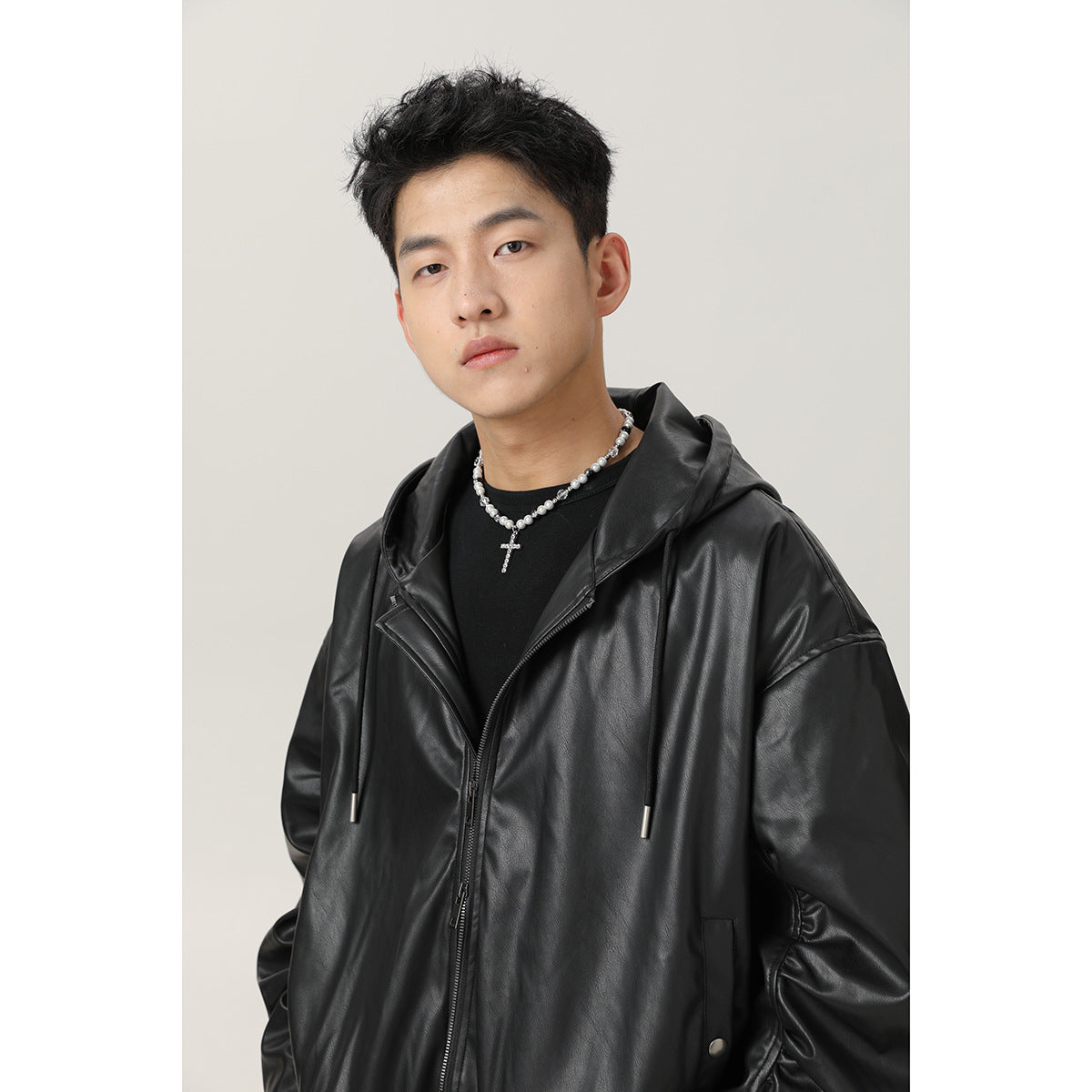 Close view of a model wearing a black hooded zip jacket with drawstrings and a glossy finish.