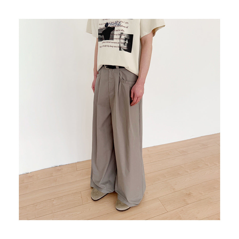 Model in gray wide-leg pleated trousers, cropped three-quarter view showing side pocket and wide leg