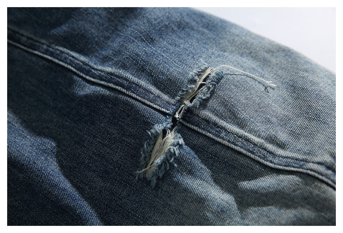 Close-up of a distressed split with loose threads across a seam in blue denim.