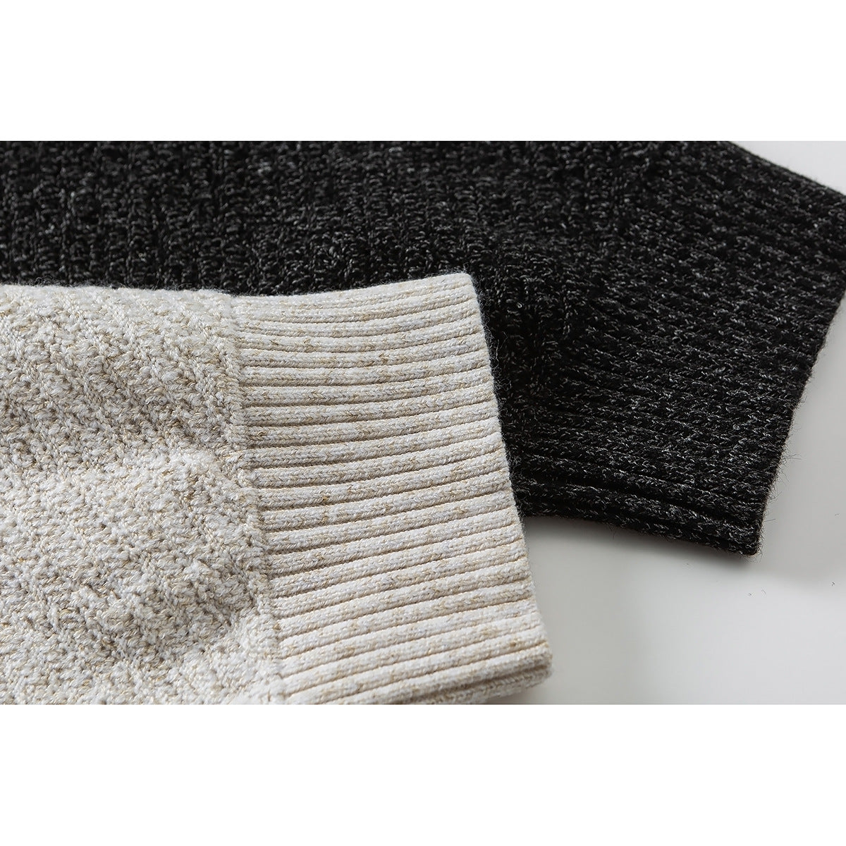 Close-up of ribbed cuffs on cream and charcoal knit pullovers.