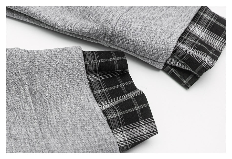 Close-up of gray shirt cuffs with black-and-white plaid fabric extending from the sleeves.