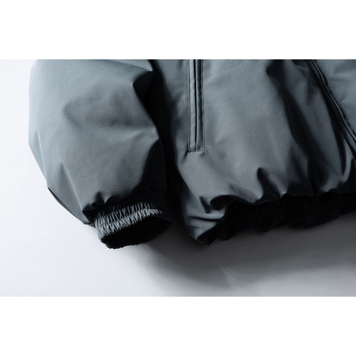 Close-up of the charcoal gray jacket's elastic sleeve cuff and gathered hem.