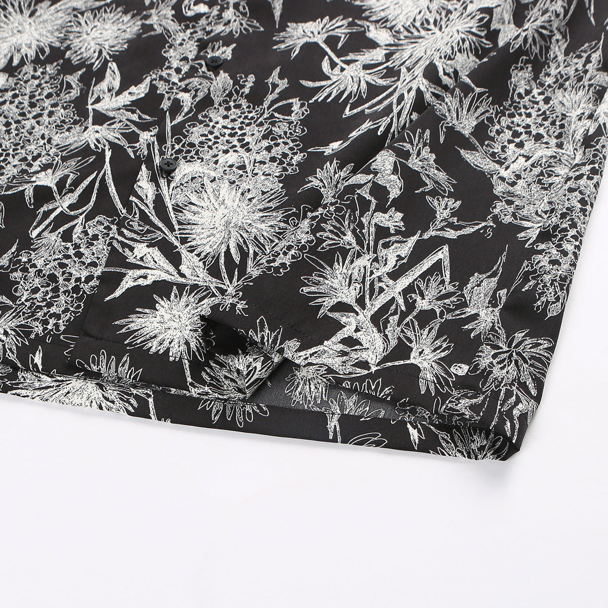 Close-up of the shirt's printed fabric, short sleeve and hem against a white background.