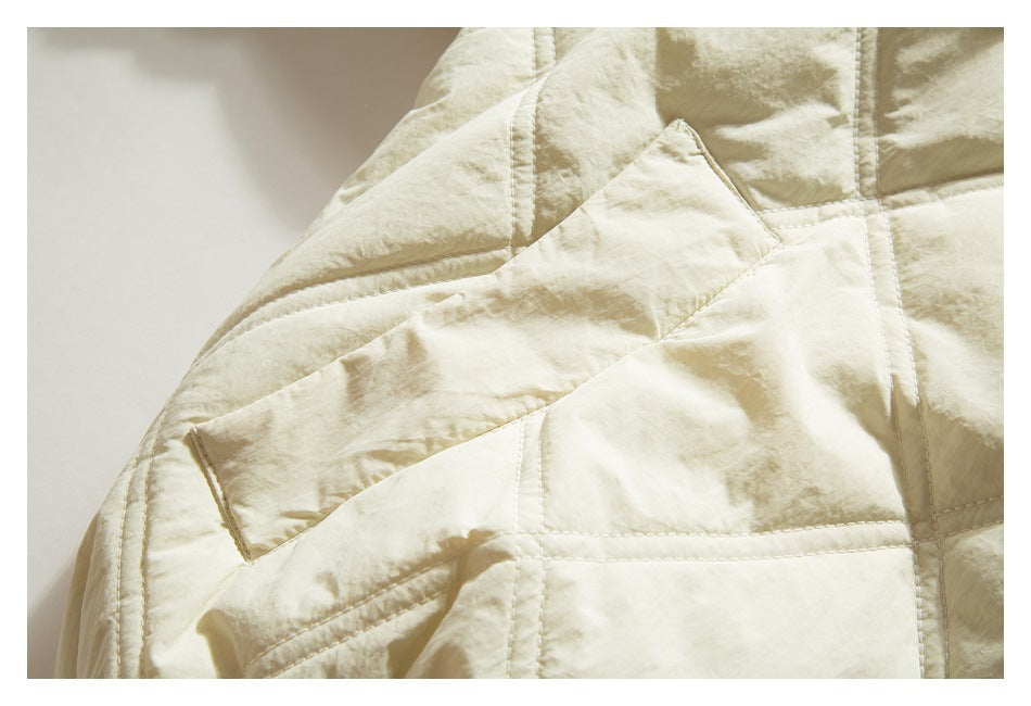Close-up of an ivory quilted jacket showing a diagonal seam and stitched panels.