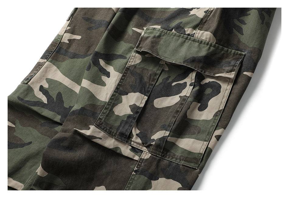 Close-up of a large flap cargo pocket on olive, black, and tan camouflage pants.