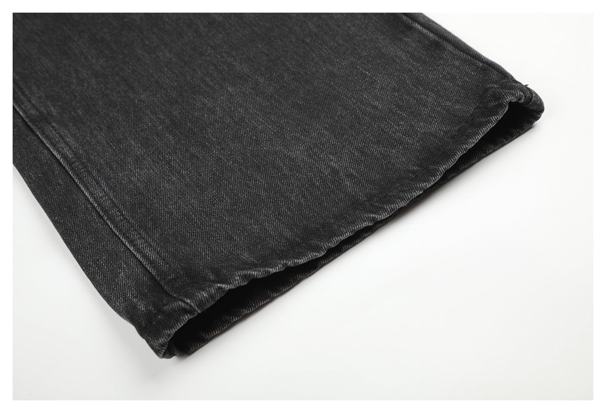 Close-up of the folded hem of charcoal-black denim jeans with visible stitching.