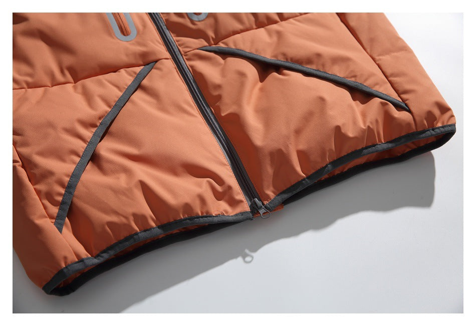 Close-up of the orange vest's lower front, showing the center zipper, curved pocket trim and dark hem binding.