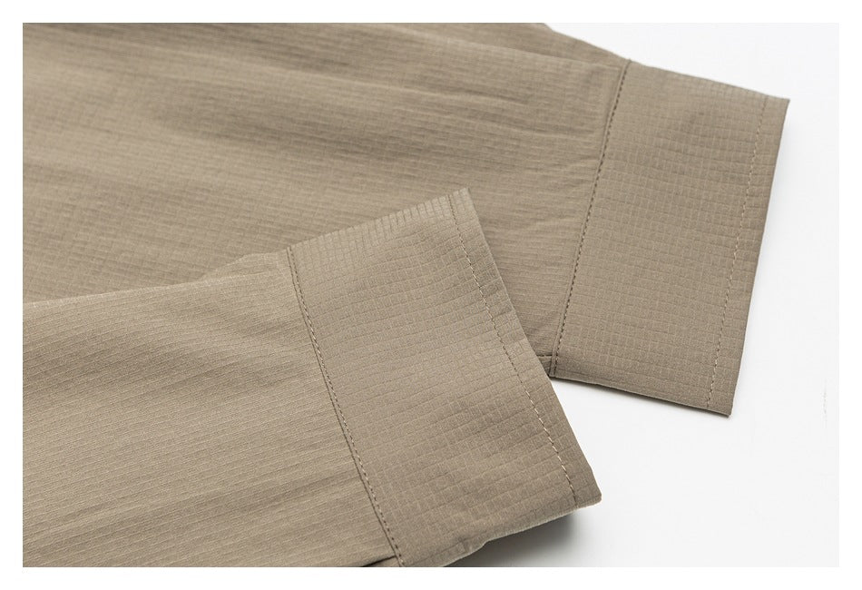 Close-up of taupe shirt sleeve cuffs with stitched edges and a subtle grid texture.