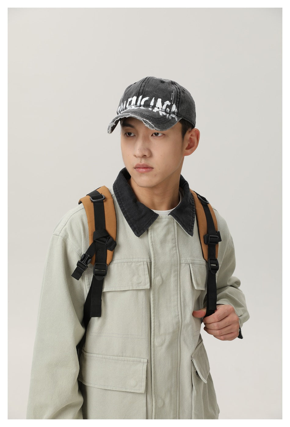 Close view of a model wearing a pale gray-green utility jacket with a dark collar and flap pockets.