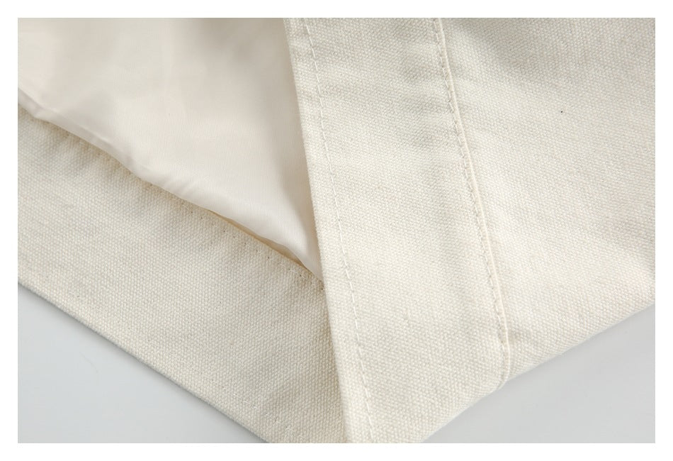 Close-up of an ivory garment seam showing the textured outer fabric beside a smooth lining.
