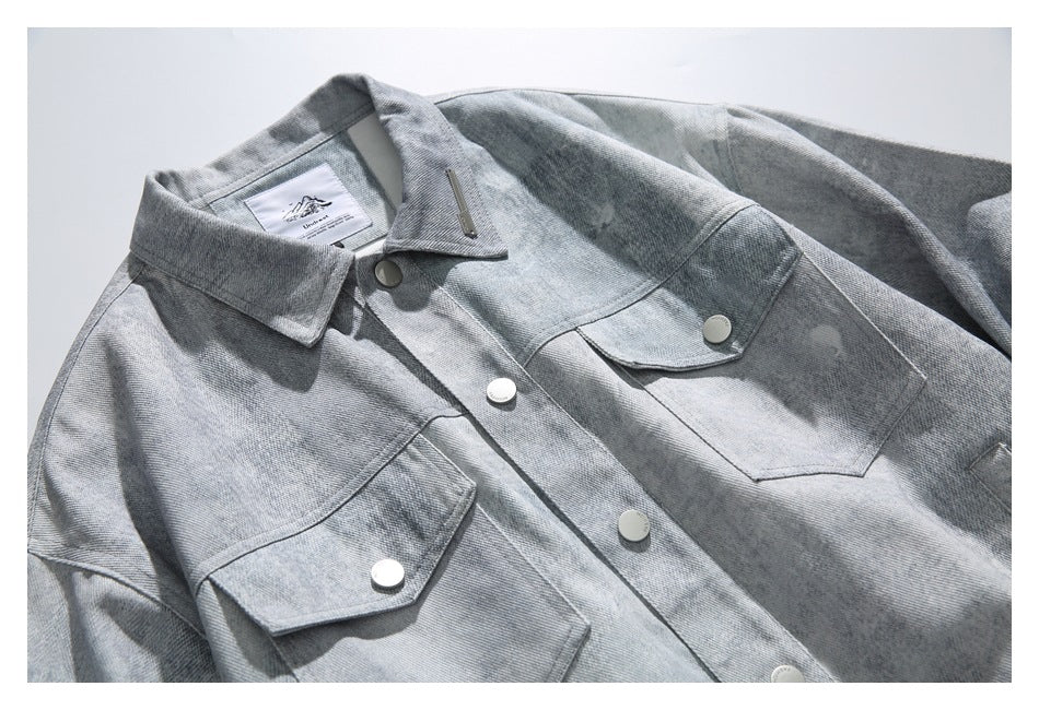 Close-up of the light gray washed jacket front, showing its collar, snap-button placket, and two flap chest pockets.