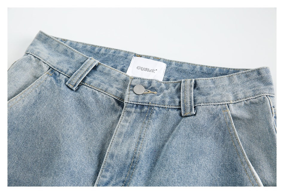 Close-up of pale blue jeans showing the waistband, button, fly stitching, belt loops and inner label.