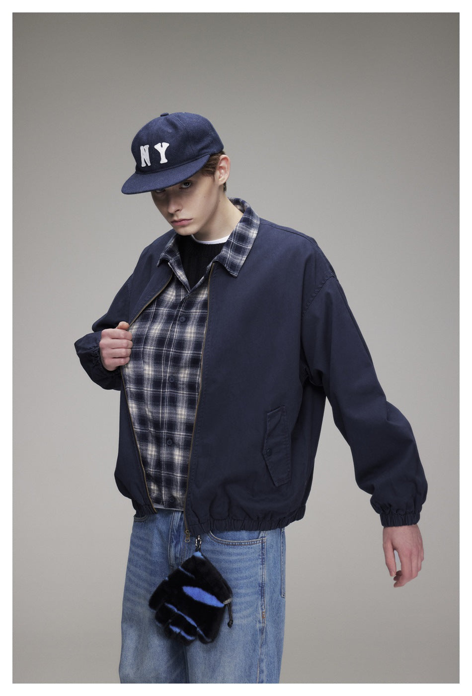 Model wearing a navy zip jacket over a gray plaid shirt, with elastic cuffs and hem.