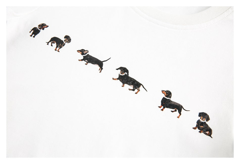 Close-up of a white T-shirt printed with a diagonal row of small black-and-tan dachshunds.
