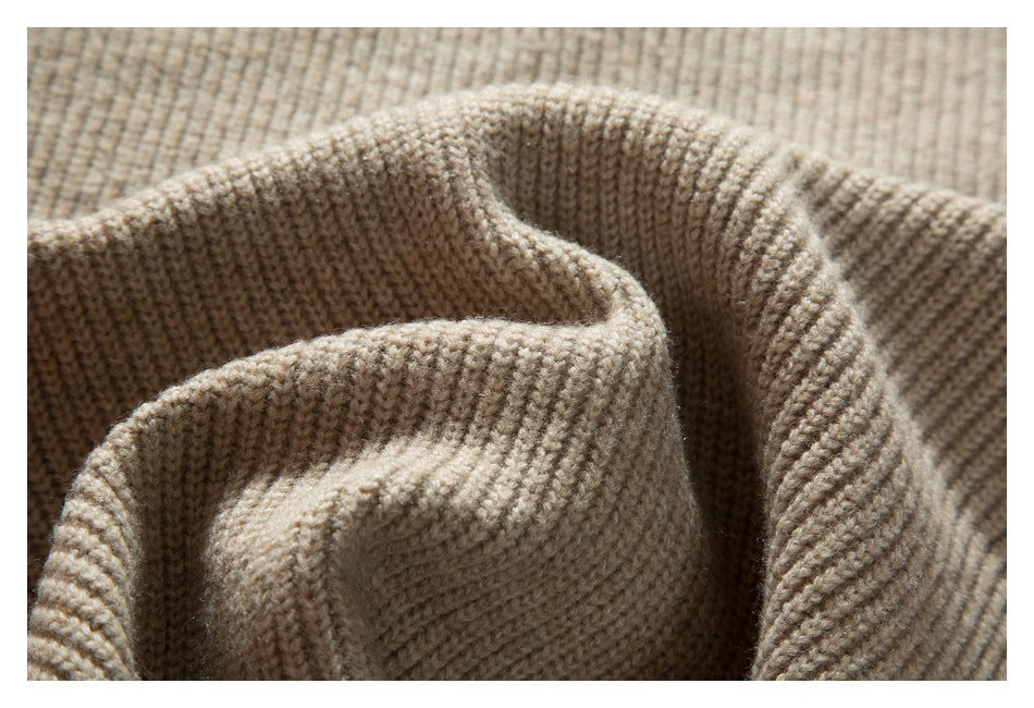 Close-up of folded beige rib-knit sweater fabric, showing its ridged texture.