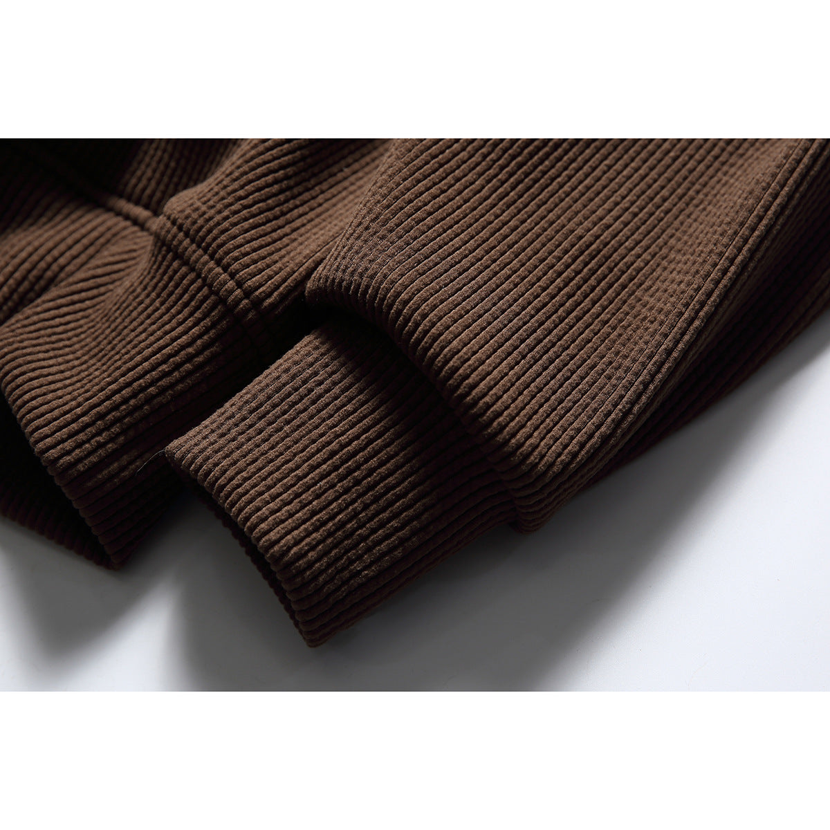 Close-up of the brown hoodie’s ribbed knit fabric and finished edge.