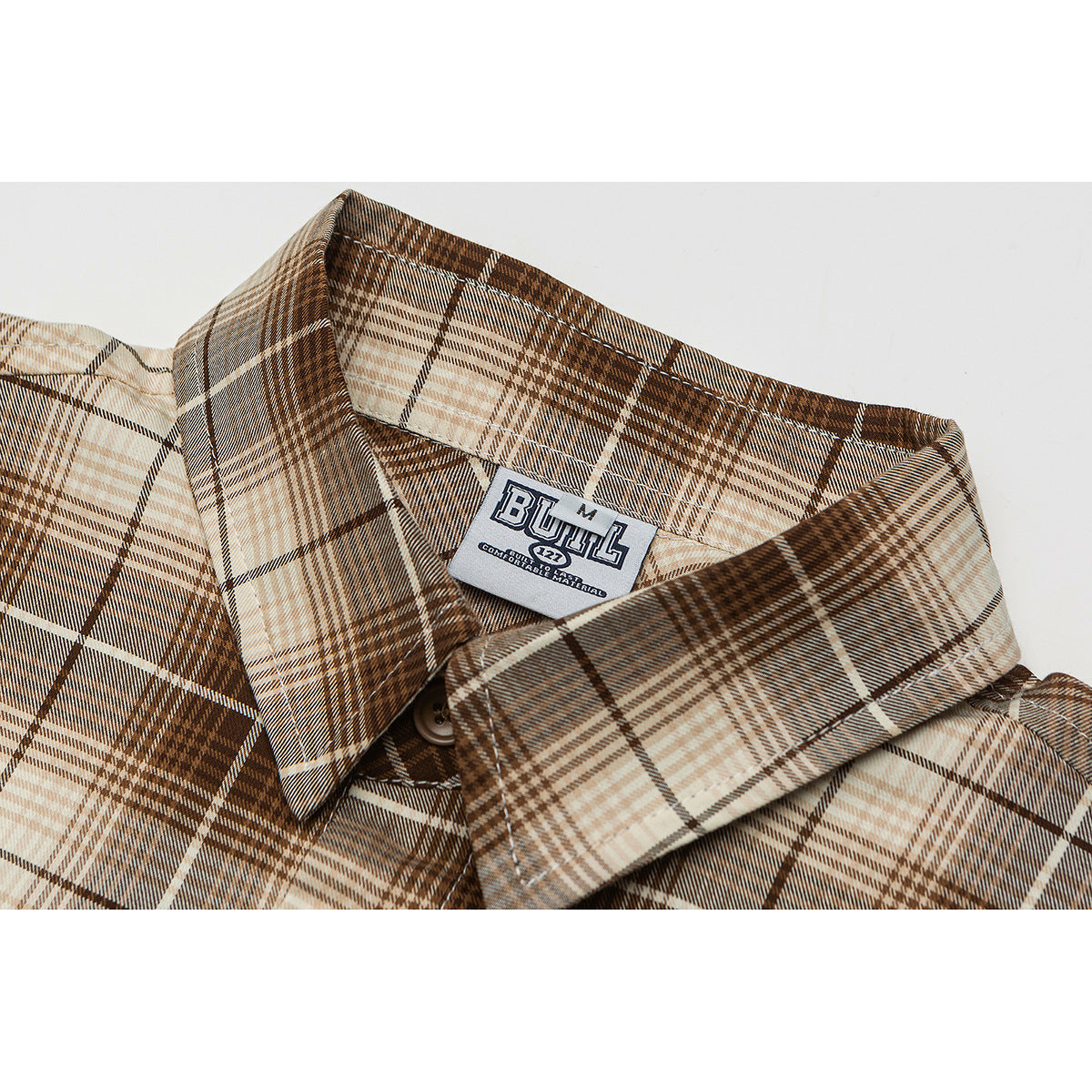 Close-up of a brown, tan and cream plaid shirt collar with a visible sewn-in neck label.