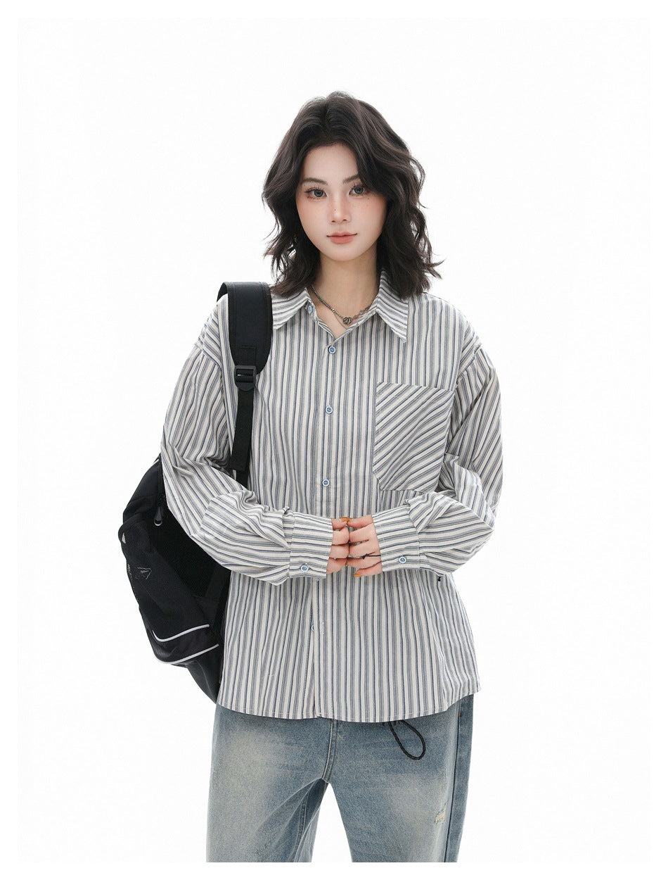 Model wearing a blue-gray striped button-up shirt with a chest pocket and light-wash jeans, shown from the front.