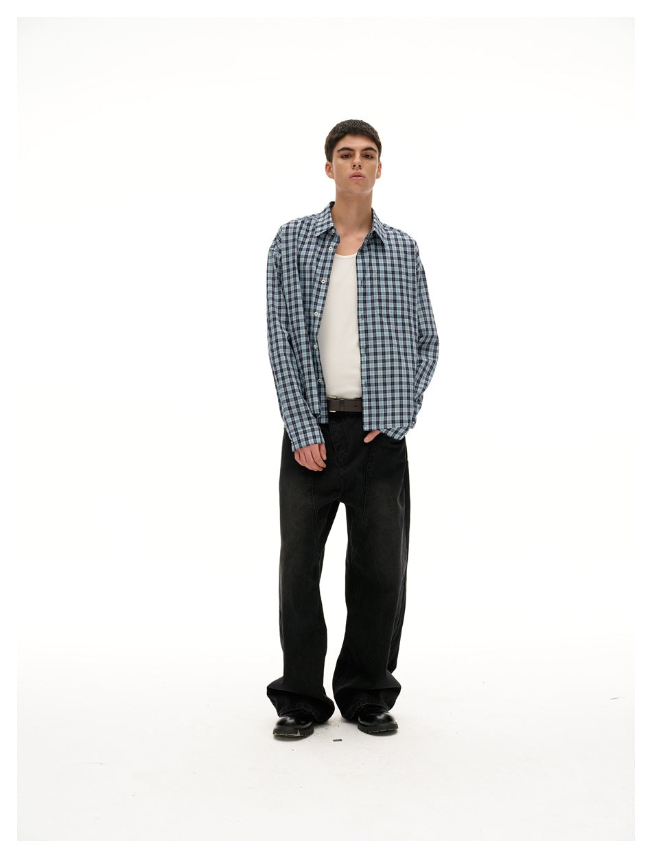 Model wearing a blue plaid shirt open over a white tank top with black wide-leg jeans and black shoes